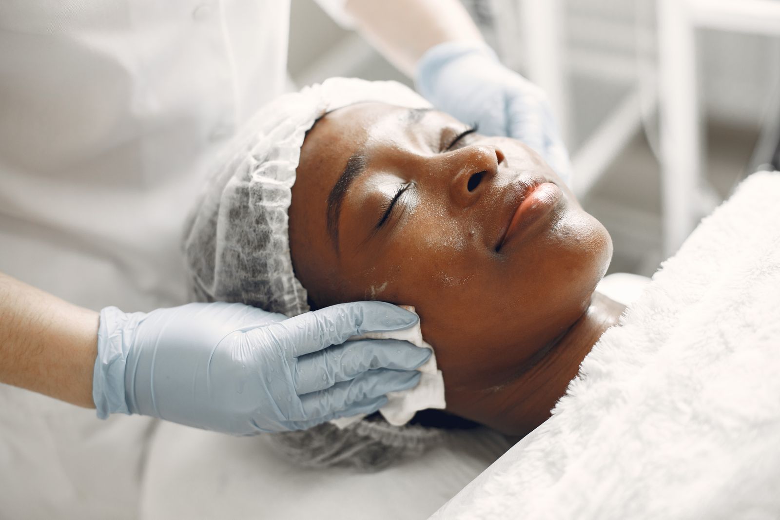 Editorial image of a gloved practitioner providing a facial treatment.