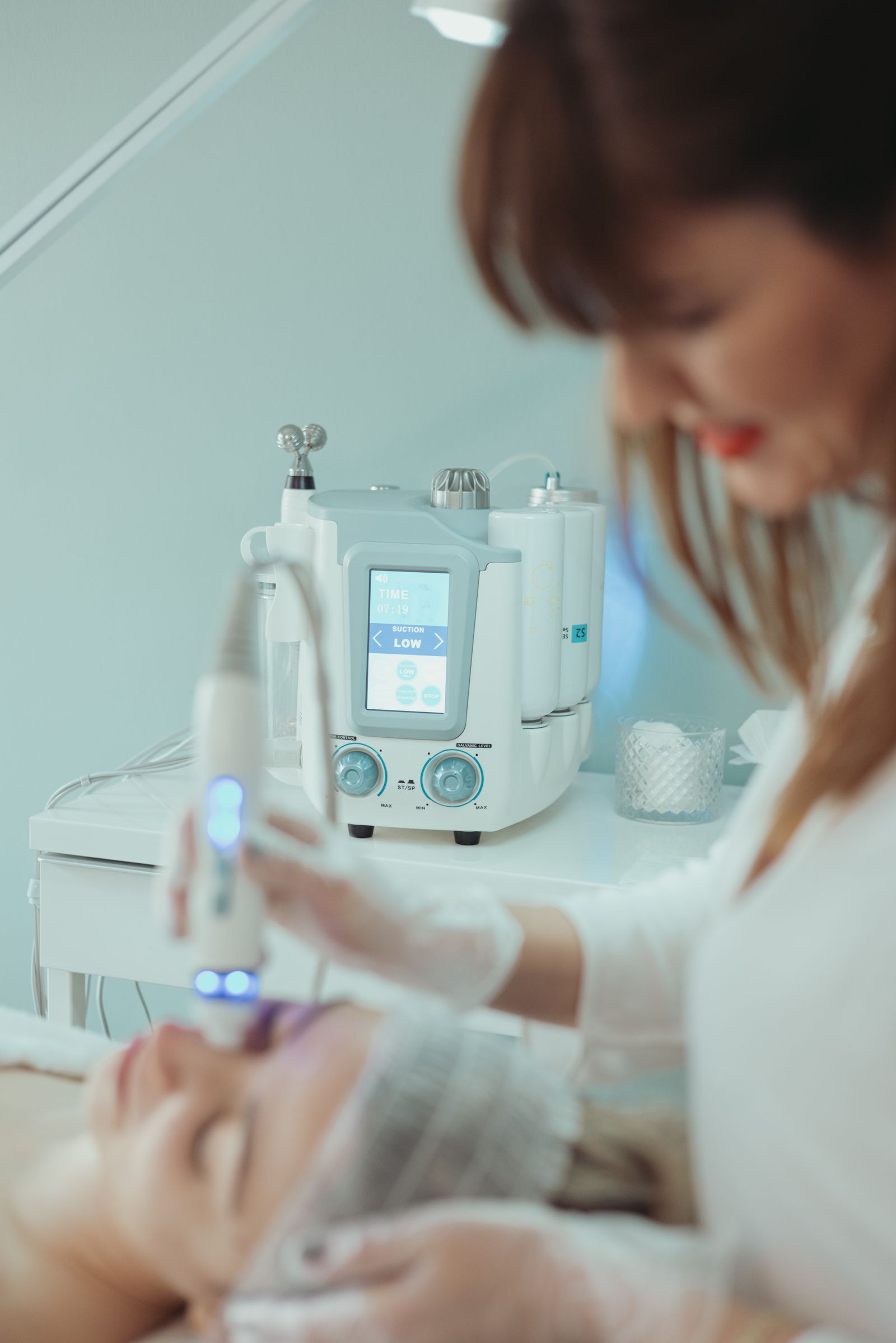 Editorial image of a hydrating facial treatment with a handheld skincare device.